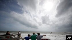 People on a boardwalk look out over the high surf from the Atlantic Ocean, in advance of the potential arrival of Hurricane Dorian, in Vero Beach, Florida, Sept. 2, 2019.