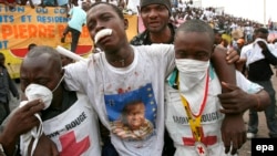 Des travailleurs de la croix rouge congolais portent un homme blessé lors des violences qui ont éclaté en marge d'un rassemblement électoral du candidat présidentiel Jean-Pierre Bemba à Kinshasa, RDC, 27 Juillet 2006. epa / NIC Bothma