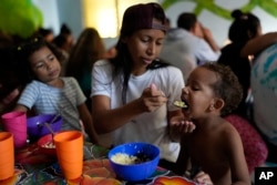 La migrante venezolana Eyla Fonseca alimenta el desayuno a su hijo Keilerth Veloz en el refugio Casa del Migrante en Tecún Umán, Guatemala, el 27 de octubre de 2024.