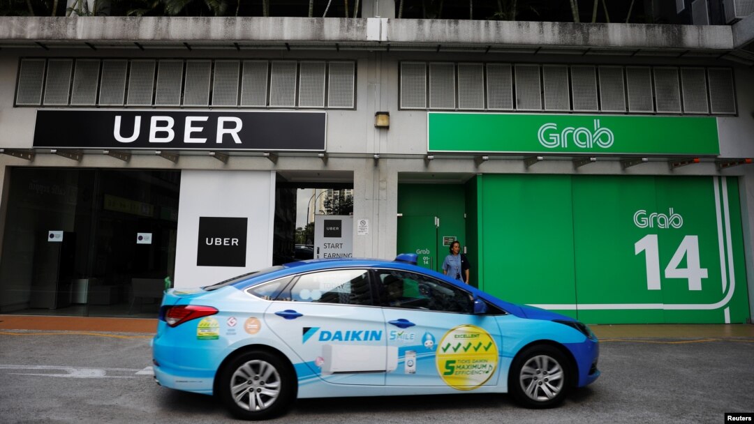 Sebuah taksi ComfortDelgro melintas di depan kantor Uber dan Grab di Singapura, 26 Maret 2018. 