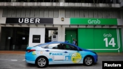 A ComfortDelgro taxi passes Uber and Grab offices in Singapore, March 26, 2018. 