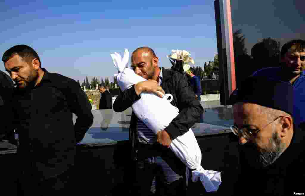 Timur Xaligov carries his 10-month-old daughter, who was killed with five other relatives, including her mother, when a rocket hit their home during the fighting over the breakaway region of Nagorno-Karabakh, in Ganja, Azerbaijan, Oct. 17, 2020.