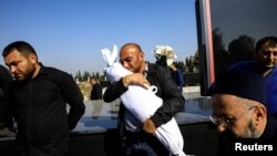 Timur Xaligov carries his 10-month-old daughter, Narin, who was killed with five other relatives, including her mother, when a rocket hit their home during the fighting over the breakaway region of Nagorno-Karabakh, in Ganja, Azerbaijan, Oct. 17, 2020. 