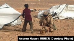 Một binh sĩ Jordan giúp một cậu bé Syria tị nạn dựng lều 