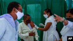 People wear masks as a precaution against the coronavirus as a health worker administers the COVISHIELD vaccine at a government hospital in Hyderabad, India, April 19, 2021.