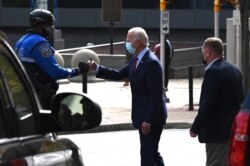 FILE - Then-Democratic presidential candidate Joe Biden fist bumps a police officer as he departs The Queen theater after taping an interview, in Wilmington, Delaware, Oct. 19, 2020.