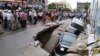 ​​Onlookers watch the cars sink in a hole by a construction site by Phnom Penh's Olympic Stadium after a heavy rain on Wednesday, June 8, 2016. (Courtesy of SBN)