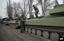 FILE - Russia-backed separatist fighters stand on artillery pieces, part of a unit moved away from the front lines, in Yelenovka, near Donetsk, Ukraine, Feb. 26, 2015.