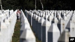 A Bosnian Muslim woman reacts as she walks among gravestones at the memorial centre of Potocari near Srebrenica, 150 kms north east of Sarajevo, Bosnia, Aug. 14, 2018.