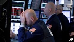 Trader Fred DeMarco, left, works with colleagues in a booth on the floor of the New York Stock Exchange, March 22, 2018. 