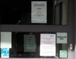 Signs at the entrance of the County Oak Medical Centre GP practice in Brighton, England, Feb. 11, 2020. The center has been temporarily closed following reports a member of staff there was one of those infected with coronavirus.