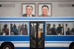 Commuters ride a bus past the portraits of late North Korean leaders Kim Il Sung and Kim Jong Il, on Kim Il Sung square in Pyongyang on June 18, 2019. (Photo by Ed JONES / AFP)