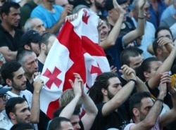 Opposition demonstrators wave a Georgian national flag as they gather in front of the Georgian Parliament building in Tbilisi, Georgia, June 21, 2019.