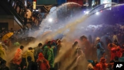 Pro democracy demonstrators face water canons as police try to clear the protest venue in Bangkok, Thailand, Oct. 16, 2020.
