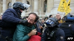 A protester bites the hand of a police officer in riot gear during a demonstration called by the French Farmers&#39; Confederation union to protest against the inauguration of the 64th edition of the European Commodities Exchange at the Grand Palais, in Paris, France.