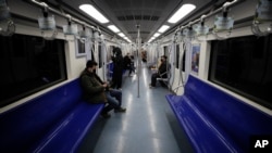 FILE -Commuters ride a subway during the morning rush hour in Beijing, Feb. 17, 2020. The economic fallout from the coronavirus outbreak may be just beginning. Companies say their bottom lines will take a hit, and governments are ramping up stimulus.