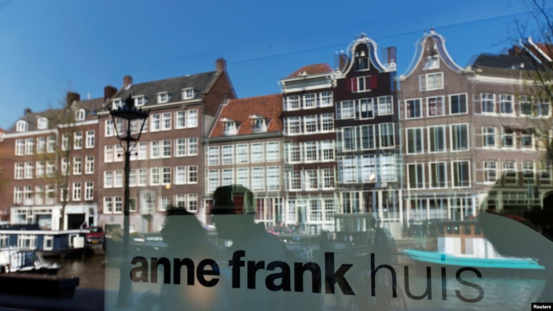 FILE - Reflections of tourists and canal houses are seen in the window of the Anne Frank museum in Amsterdam, April 24, 2013. 