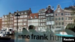 FILE - Reflections of tourists and canal houses are seen in the window of the Anne Frank museum in Amsterdam, April 24, 2013. 