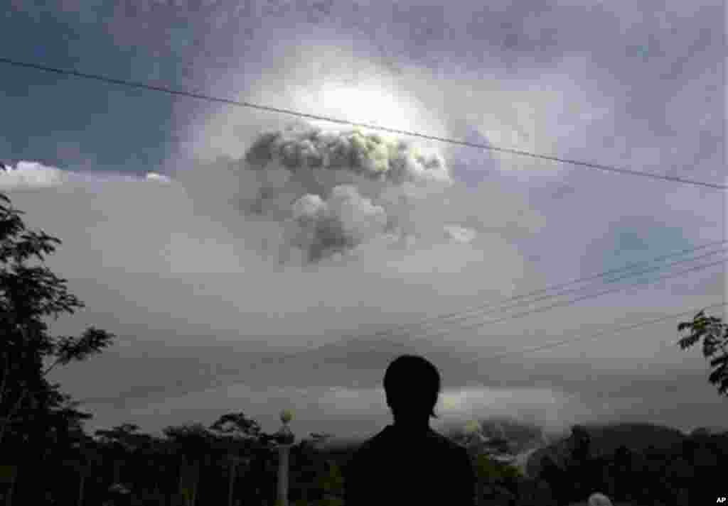 An Indonesian man watches as Mount Merapi erupts in Kepuharjo, Yogyakarta, 3 Nov 2010 (AP)