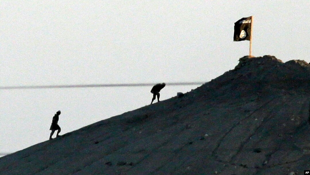 Militan-militan Negara Islam (ISIS) usai memasang bendera kelompok mereka di Kobani, Suriah. 