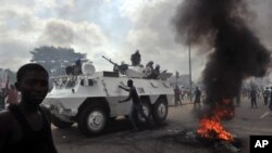 UN peacekeepers drive past supporters of Alassane Ouattara as they demonstrate and burn tires in the Abobo neighbourhood in Abidjan.