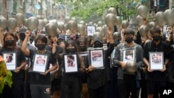 Anti-coup protesters holding pictures of those who died during a protest against the military offer prayers for them, in Yangon, Myanmar, Monday, April 5, 2021. Threats of lethal violence and arrests of protesters have failed to suppress daily demonstrations across Myanmar demand