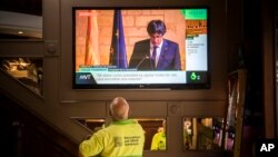 Orang-orang di bar menyaksikan pidato Pemimpin Catalan Carles Puigdemont lewat layar lebar di Barcelona, Spanyol (10/26).