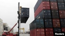 FILE - Workers load containers onto trucks from a cargo ship at a port in Jaragua do Sul, Santa Catarina state, Brazil, Oct. 22, 2015. 