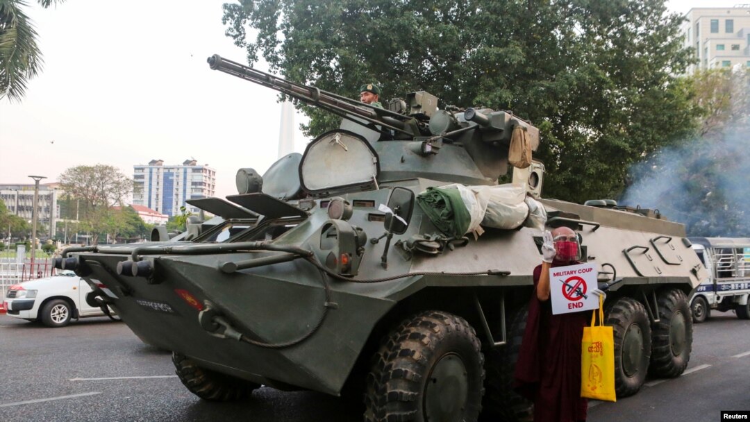 Seorang biksu Buddha memegang tanda berdiri di samping kendaraan lapis baja selama protes terhadap kudeta militer, di Yangon, Myanmar, 14 Februari 2021. (Foto: Reuters)