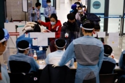 28일 한국 인천공항에서 방역 관계자들이 입국자들을 대상으로 신종 코로나바이러스 방역 절차를 진행하고 있다.
