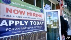 FILE - A man walks into a restaurant displaying a "Now Hiring" sign, in Salem, N.H., March 4, 2021.