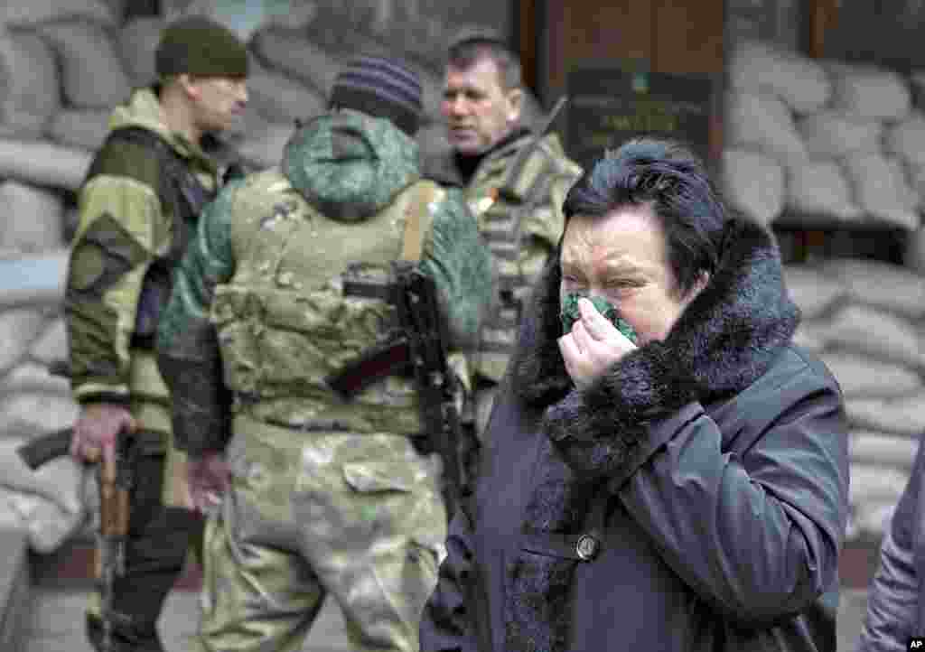 A woman reacts as she walks past pro-Russian rebels guarding the Zasyadko mine in Donetsk, March 4, 2015.