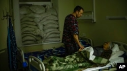 FILE - Dr. Ivan Mozhaiev attends to a patient during morning rounds at Pokrovsk hospital in Pokrovsk, Ukraine, on May 22, 2022. The country's health system is bracing for a second winter of war.