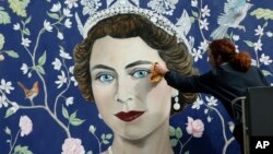 Un ouvrier installe une peinture mural fait par Frederick Wimsett, qui représente un portrait de la reine Elizabeth II pour marquer son 90e anniversaire, au centre-ville de Londres, le 19 avril 2016.