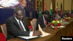 South Sudanese rebel leader Riek Machar, left, and South Sudan's President Salva Kiir sign a ceasefire and power sharing agreement in Khartoum, Sudan, Aug. 5, 2018.