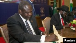 Le chef des rebelles sud-soudanais, Riek Machar, à gauche, et le président du Soudan du Sud, Salva Kiir, signent un accord de cessez-le-feu et de partage des pouvoirs à Khartoum, au Soudan, le 5 août 2018.