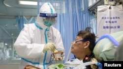 A nurse in a protective suit feeds a novel coronavirus patient inside an isolated ward at Zhongnan Hospital of Wuhan University, during the Lantern Festival, which marks the end of the Chinese Lunar New Year celebrations, in Wuhan, Hubei province,…