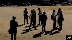 Tourists from China stand on parched grass from the lack of rain on Parliament Square, during what has been the driest summer for many years, in London, Britain, July 24, 2018.