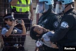 Policija privodi čovjeka nakon što je nekoliko demonstranata probilo bezbjednosnu ogradu. (Foto: REUTERS/Adrees Latif)