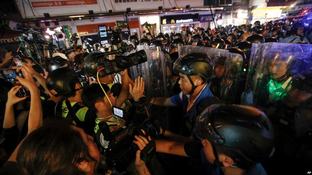 Para wartawan merekam polisi sedang membersihkan jalanan di Hong Kong, 7 Juli 2019.