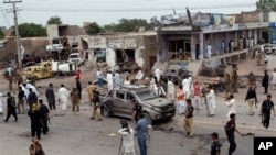 Petugas keamanan Pakistan dan para wartawan mengerumuni lokasi ledakan bom mobil di Peshawar, Pakistan, Minggu pagi (30/6).