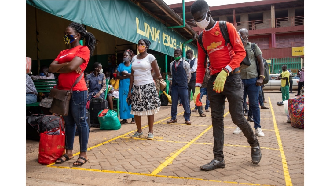 People queue to buy bus tickets while adhering to social distancing measures and wearing masks to curb the spread of the coronavirus at the Namirembe Bus Park in Kampala, Uganda, June 4, 2020.