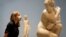A museum employee looks toward a marble statue of Crouching Venus, Roman, 2nd century AD, during a press view at The British Museum in London.