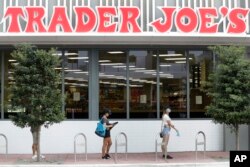 People practice social distancing as they wait in line to enter a grocery store, April 7, 2020, in Miami Beach, Florida.