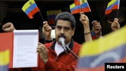 Venezuela's President Nicolas Maduro shows a document with the details of a "constituent assembly" to reform the constitution during a rally at Miraflores Palace in Caracas, Venezuela, May 23, 2017.