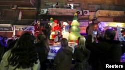 A man dressed as Santa Claus distributes gifts to children during a Christmas parade in Damascus, Syria, on Dec. 27, 2015. 