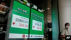 A man wearing face mask walks past a bank electronic board showing the Hong Kong share index at Hong Kong Stock Exchange, May 14, 2020. 