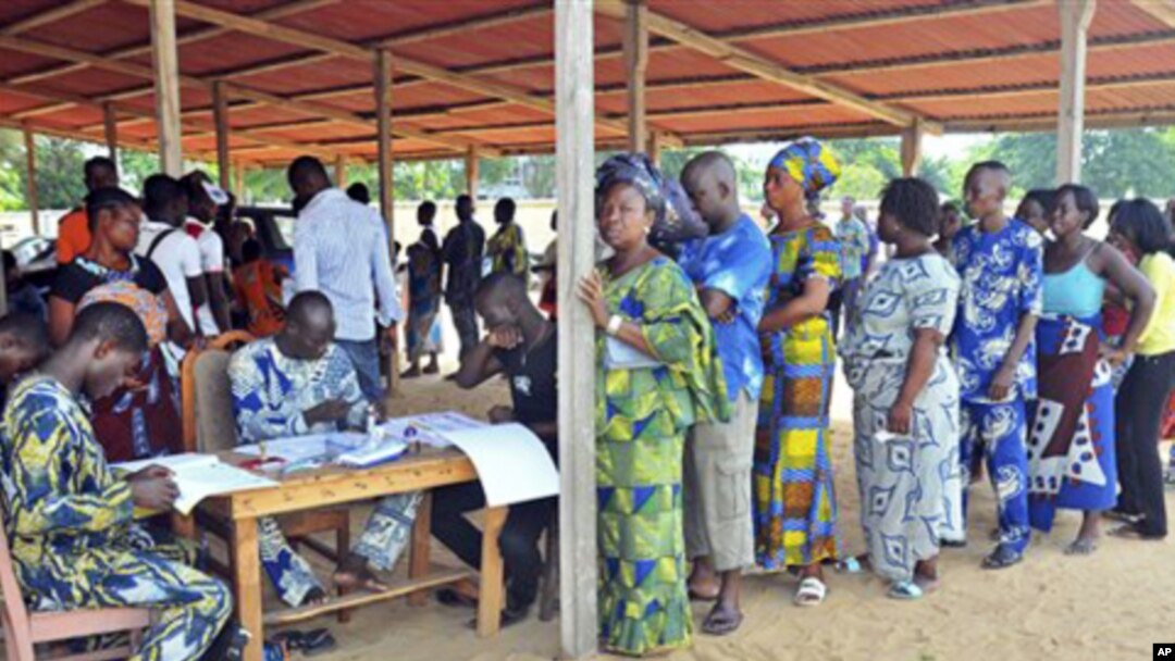 Men and women stand in line to cast their ballots at the city of Cotonou, Benin, March 13, 2011