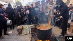 A volunteer stirs a food pot as Palestinians wait to collect humanitarian aid portions, in al-Shati camp near Gaza City on Dec. 26, 2024.