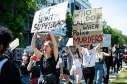 People protest in Berlin, Germany, May 31, 2020 after the violent death of the African-American George Floyd by a white policeman in the USA against racism and police violence, among other things with a sign "Who do call when police murders".
